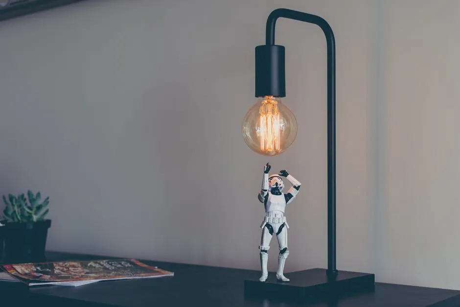 A miniature figure reaching toward a light bulb.